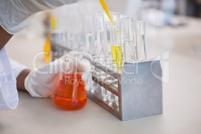 Scientist pouring orange fluid in test tube