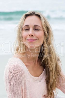 Smiling pretty blonde relaxing on the sand