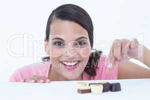 Pretty brunette peeking at chocolate looking at camera