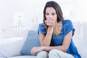 Thoughtful beautiful brunette sitting on the couch