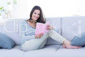 Smiling beautiful brunette relaxing on the couch and reading a b
