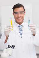 Smiling scientist examining precipitates in tubes