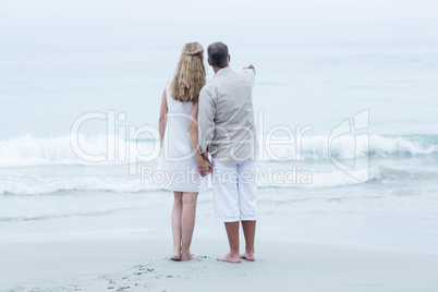 Happy couple standing by the sea and holding hands