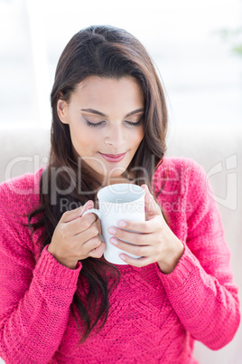 Smiling beautiful brunette relaxing on the couch and holding mug