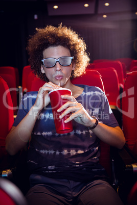 Young man watching a 3d film and drinking soda