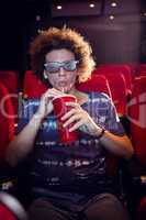 Young man watching a 3d film and drinking soda