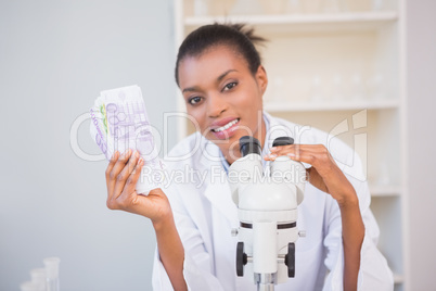 Smiling scientist holding money and looking at camera