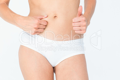 Woman with little fat on her belly with thumb up