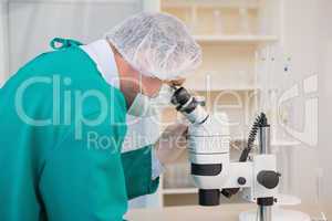 Scientist in scrubs using microscope