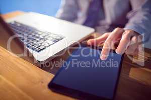 Businessman using laptop and tablet at desk