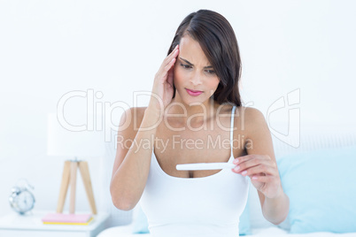 Anxious brunette woman looking her pregnancy test
