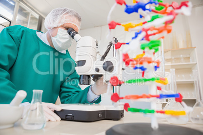 Scientist in scrubs using microscope