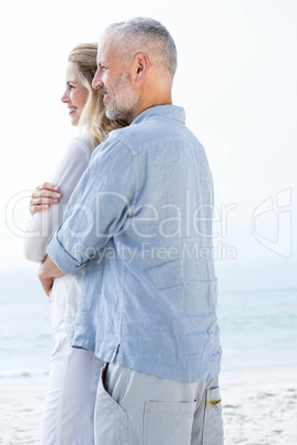 Happy couple hugging each other and looking at the sea