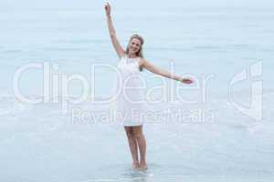 Smiling blonde in white dress standing by the sea