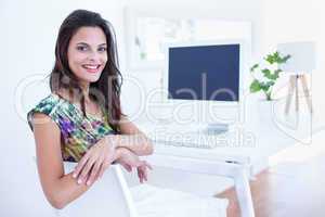 Smiling beautiful brunette sitting in front of her computer