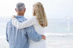 Happy couple hugging each other and looking at the sea