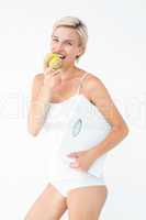 Happy woman holding scales eating apple