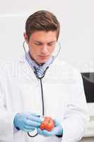 Scientist listening apple with stethoscope