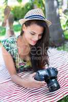 Smiling beautiful brunette lying on the blanket and taking pictu