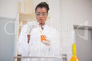 Concentrated scientist examining orange fluid