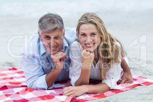 Happy couple lying on a blanket and smiling at camera