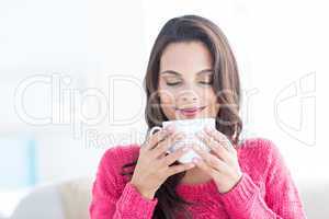 Smiling beautiful brunette relaxing on the couch and holding mug