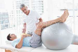 Therapist helping his patient with exercise ball