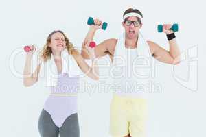 Geeky hipster couple lifting dumbbells in sportswear