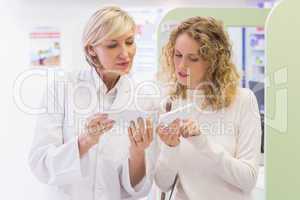 Pharmacist holding a bottle of drugs talking to customer