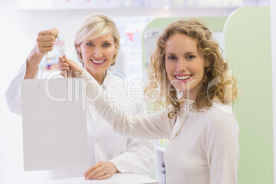 Pharmacist and costumer holding paper bag