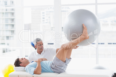 Therapist helping his patient with exercise ball