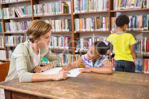 Teacher helping pupil in library