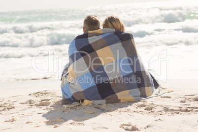 Happy couple wrapped up in blanket