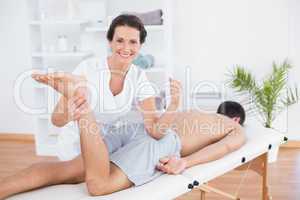 Physiotherapist doing leg massage and smiling at camera