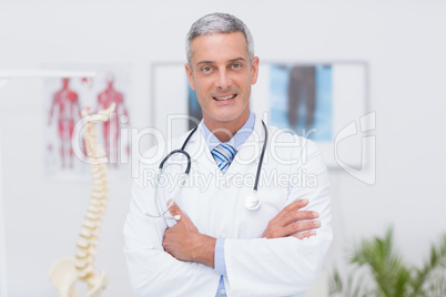 Happy doctor looking at camera with arms crossed