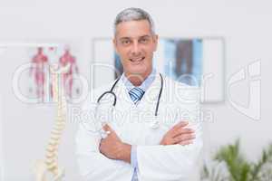 Happy doctor looking at camera with arms crossed