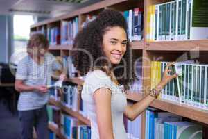 Student picking a book from shelf in library