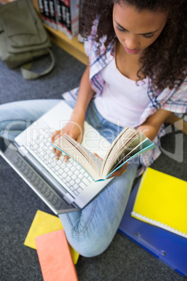 Student sitting on floor in library using laptop Student sitting on floor in library using laptop