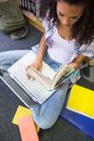 Student sitting on floor in library using laptop