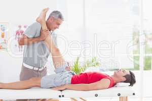 Physiotherapist doing leg stretching to his patient