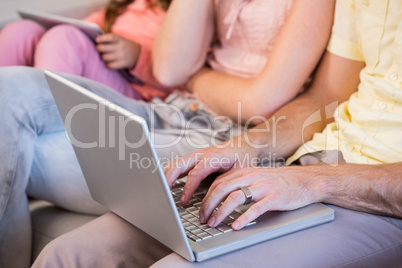 Family on couch using tablet pc and laptop