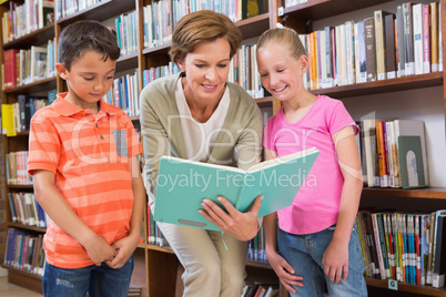 Teacher reading book with pupils at library