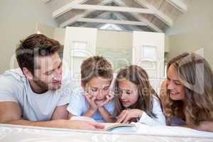 Happy family on the bed reading book