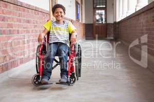 Cute disabled pupil smiling at camera in hall