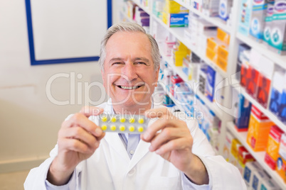 Senior pharmacist holding up blister packs