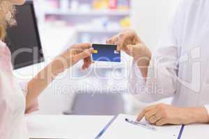 Pharmacist giving credit card to costumer