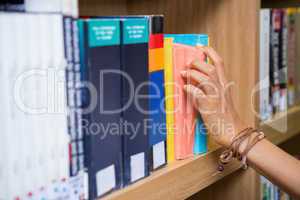 Student picking a book from shelf in library