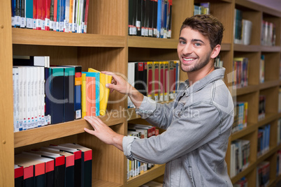 Student picking a book from shelf in library