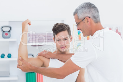 Doctor stretching a young man arm