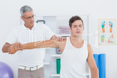 Doctor stretching a young man arm